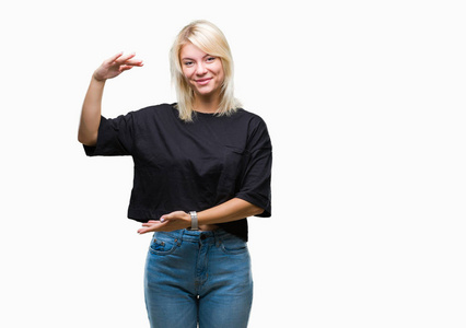 年轻漂亮的金发女人在孤立的背景上做手势，双手显示大尺寸的标志符号。 微笑着看着相机。 测量概念。