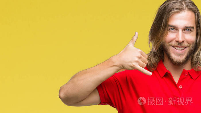 年轻的英俊男子,长发在孤立的背景上微笑,用手和手指做电话手势,就像