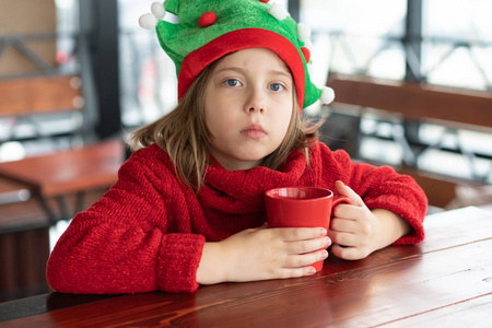 咖啡馆里一个穿红色毛衣的小女孩的肖像