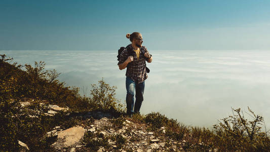徒步旅行者爬到山顶，看着云的一侧。 旅游动机旅游搜索球童流浪旅游概念