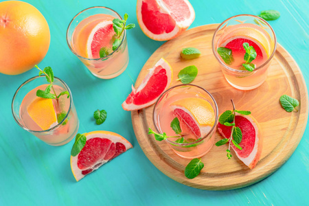 新鲜的粉红色酒精鸡尾酒，葡萄柚，冰和薄荷，喝眼镜和配料在蓝色的绿松石桌子上，有选择的焦点，浅深的领域。