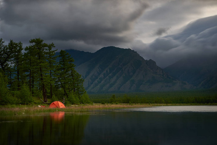 橙色帐篷在湖的海岸在晚上