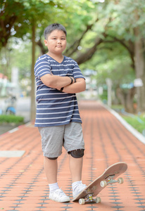 肥胖男孩站在健身公园的滑板上，为孩子们积极的户外运动。