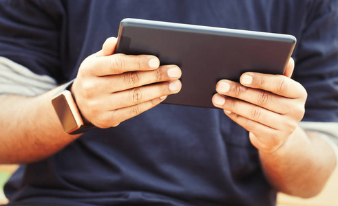 非洲黑人男子的双手戴着时髦的智能手表，在平板电脑上工作。现代小工具，让你始终保持连接到互联网，社交媒体或遥远的工作从每一个软件。