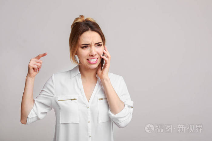 不快乐的愤怒的女人在电话里通过背景交谈