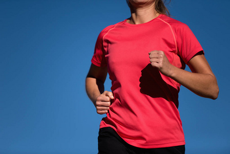 女运动员穿着红色T恤蓝天背景跑步