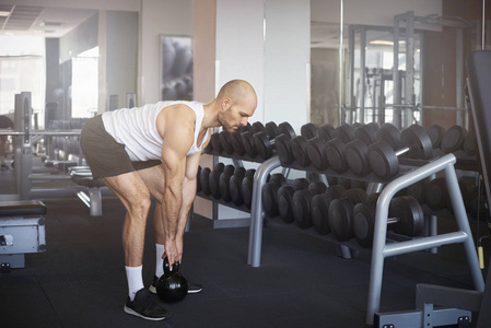 一个人在健身房锻炼时使用哑铃的全长镜头。