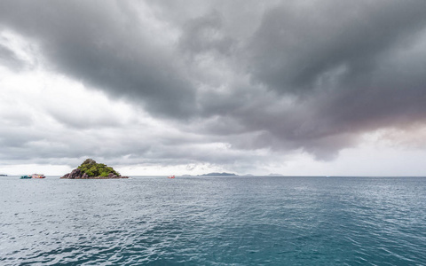 美丽的风景小岛上有旅游船，雨下得很近，天气很危险