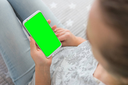 绿色屏幕智能手机。女人手拿着手机的模拟图像。色度键。特写