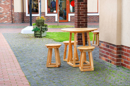 夏季咖啡厅。木制的桌椅站在商店橱窗附近的鹅卵石人行道上。城市设计
