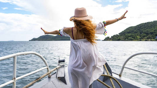 红发女孩穿着白色连衣裙在游船上逗留，并在靠近缆车的普吉岛旅行