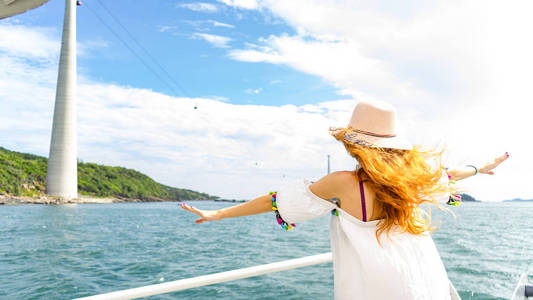 红发女孩穿着白色连衣裙在游船上逗留，并在靠近缆车的普吉岛旅行
