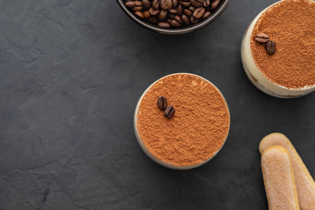 美味的意大利甜点提拉米苏, 巧克力, 可可和咖啡豆的黑色背景。具有复制空间的顶部视图