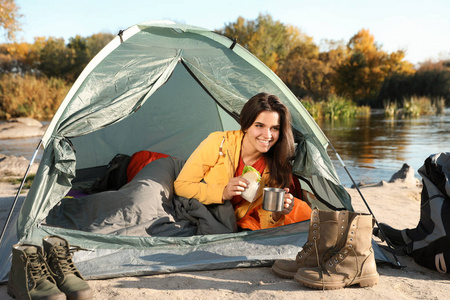 年轻女子在露营帐篷里的睡袋里吃早餐