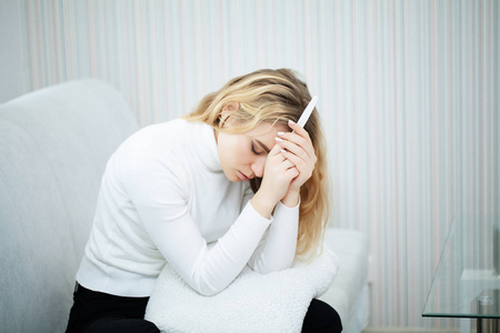 怀孕测试呈阳性。年轻女子在家中看孕检结果后感到郁闷和悲伤