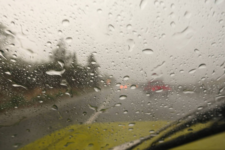 在高速公路上行驶时，突然下起了倾盆大雨。 挡风玻璃上下着大雨。