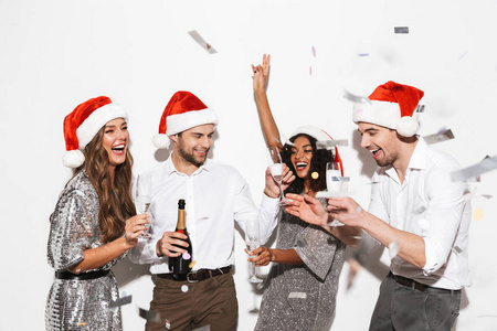 四位衣着光鲜的朋友在白色背景下孤独地站在一起庆祝新年，喝着香槟
