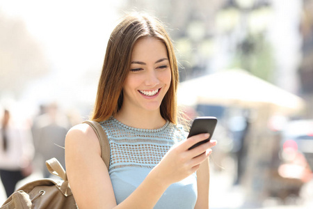 幸福的女孩走在街上检查智能手机的内容