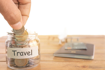 旅行预算概念。 旅行货币储蓄概念。 在钱罐里收钱旅行。 装有硬币飞机玩具和护照的钱罐。