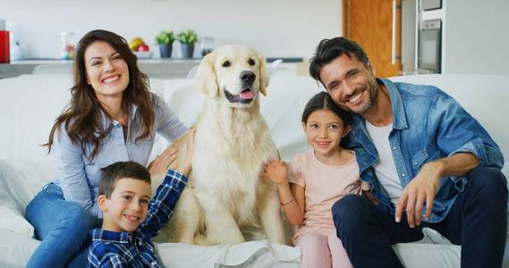 幸福家庭的肖像，一只狗在客厅里一起玩。 快乐家庭爱动物的概念童年