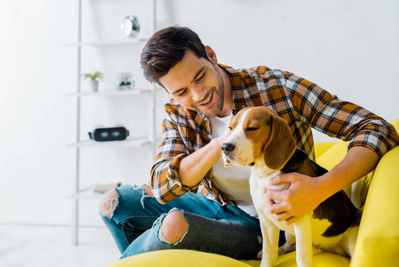 快乐的男人在家里和比格犬在一起