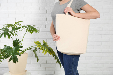 妇女与生态袋和绿色植物附近的砖墙。 设计模拟