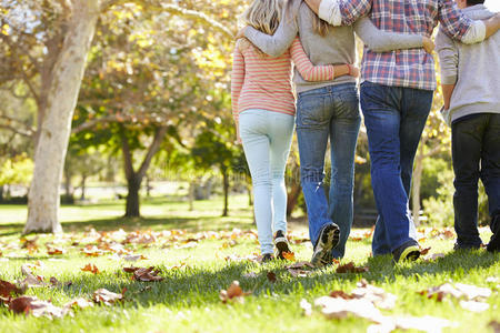 一家人穿过秋天的林地的后视图