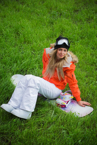 拿着滑雪板的女孩坐在草地上