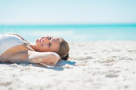 微笑的年轻女子在沙滩上晒太阳