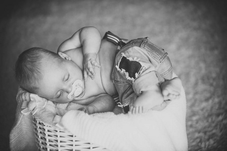 婴儿牛仔裤睡在篮子在地板上图片