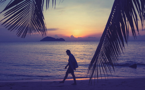 日落时分，一个男人沿着海滨散步的剪影，男人和自然概念，美丽的生活方式，自由度假，度假