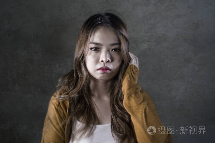 年轻的疯狂绝望悲伤的亚洲女性在孤独的黑暗背景下痛苦痛苦表情抑郁和