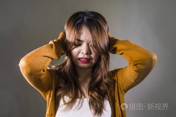年轻的疯狂绝望悲伤的亚洲女性在孤独的黑暗背景下痛苦痛苦表情抑郁和