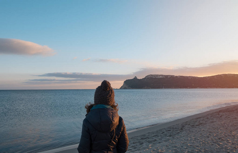 在夕阳西下的冬季撒丁岛上，女孩或女人在卡利亚里海滩上观看全景。