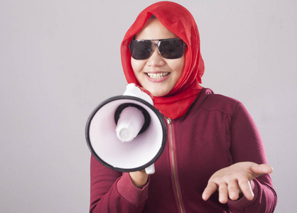 亚洲穆斯林妇女的肖像，打电话或提供带有扩音器的广告营销概念