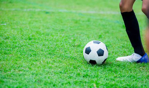 男孩足球运动员跑着在绿草上射门。 足球运动员训练或足球比赛。