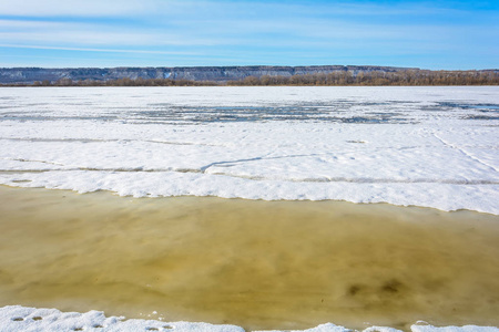 在温暖的春天阳光的影响下，河上厚厚的冰裂成了碎片