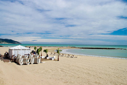 在多云的白天，海滩和海滩俱乐部在西班牙的Sitges面对地中海