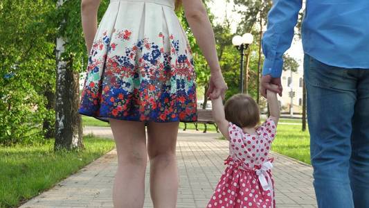 小宝宝学习如何与爸爸妈妈一起散步, 快乐的家庭漫步在夏日公园里