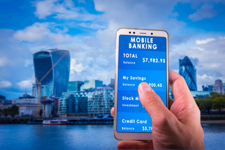 男性手抱着智能手机与手机银行在屏幕上与模糊的城市为背景