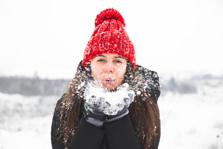 微笑的女人戴着红帽子，手里拿着雪