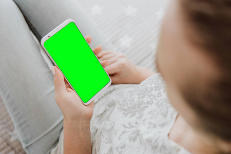 色度键。绿色屏幕智能手机。女人手拿着手机的模拟形象。特写
