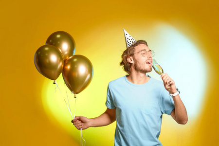快乐男人的肖像，杯子里有香槟，彩色背景上有派对气球