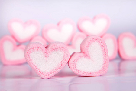 棉花糖心形在粉红色背景上的杯子与爱的概念