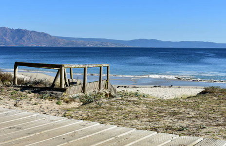海滩在海湾，木板路和沙丘植被。碧海小浪，晴空万里..晴天。加利西亚，西班牙。