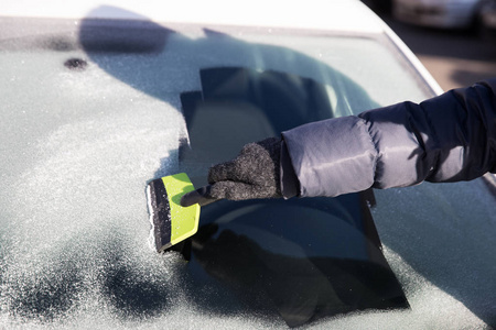 用手套把汽车的窗户从冰上擦干净