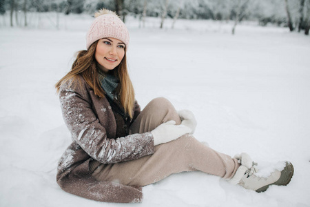 照片中, 金发女郎坐在雪中走在冬林