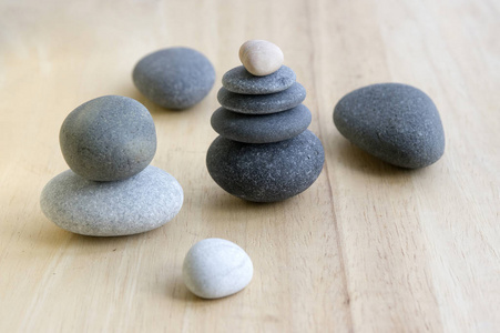 木桌上的和谐和平衡的石头，岩石，禅宗雕塑，四个灰色的鹅卵石，白色和灰色