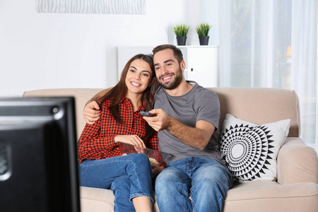幸福的年轻夫妇在家沙发上看电视
