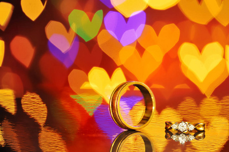 两个金色的结婚戒指，心在背景上。爱的概念，情人节的灵魂伴侣命运。